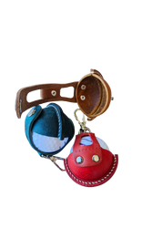 Three leather golf ball holders in green, red, and brown, each holding a golf ball. The holders feature a smooth leather finish, precise stitching, and a compact design, arranged side by side to showcase their vibrant colors and craftsmanship