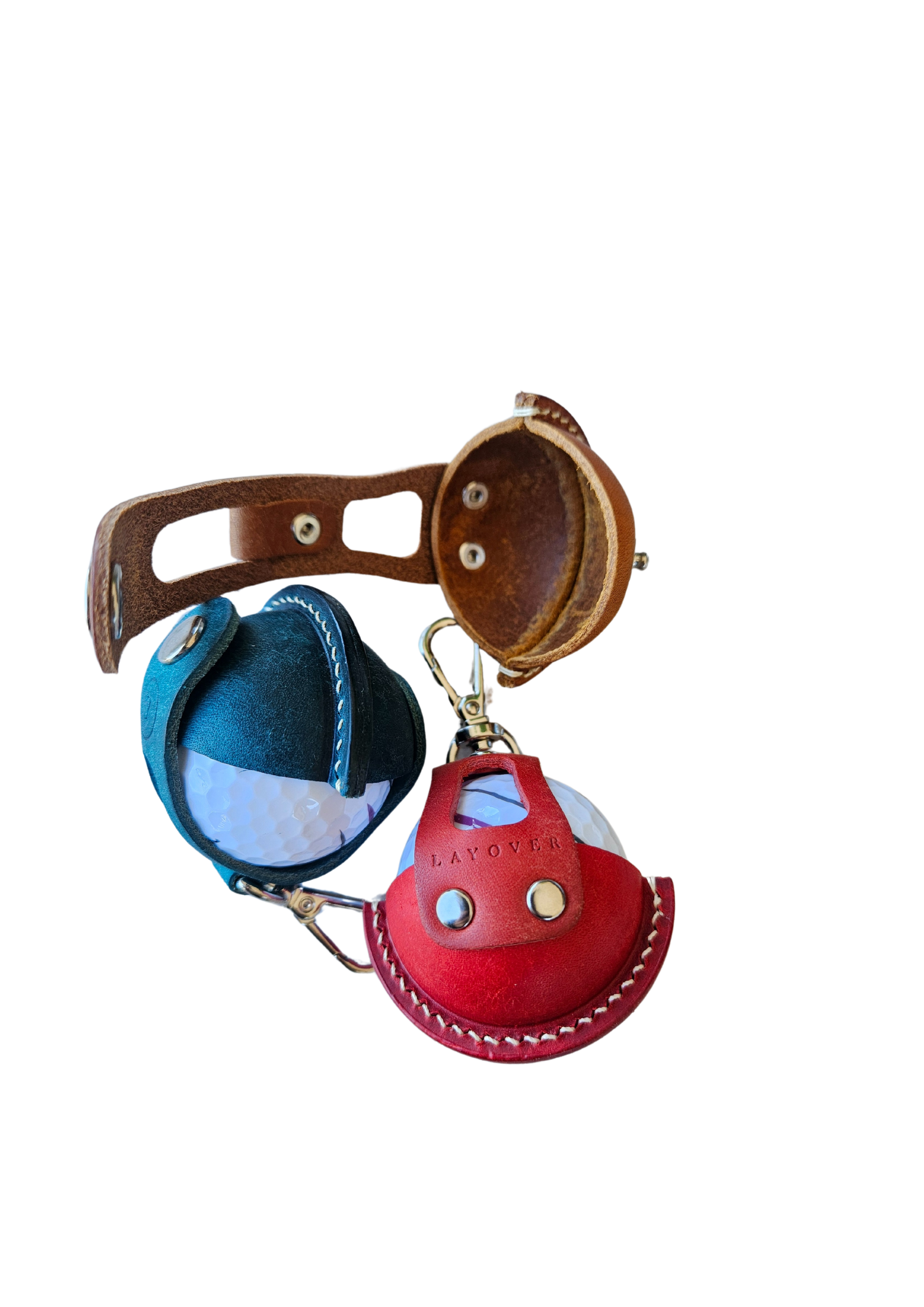 Three leather golf ball holders in green, red, and brown, each holding a golf ball. The holders feature a smooth leather finish, precise stitching, and a compact design, arranged side by side to showcase their vibrant colors and craftsmanship
