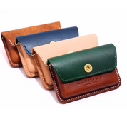 A set of handmade leather pouches in rich, vibrant colors—green, navy, and natural tan—each featuring a brass snap closure and detailed white stitching. The front pouch is embossed with the "Layover and Co." logo.